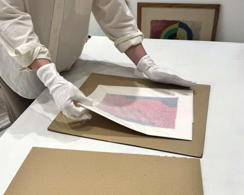 Lithographie protégée dans une pochette de papier de soie, posée à plat sur un carton rigide